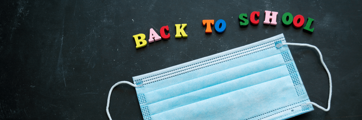 Back to school magnetic, colorful, and plastic lettering that says back to school, and blue mask on a blackboard